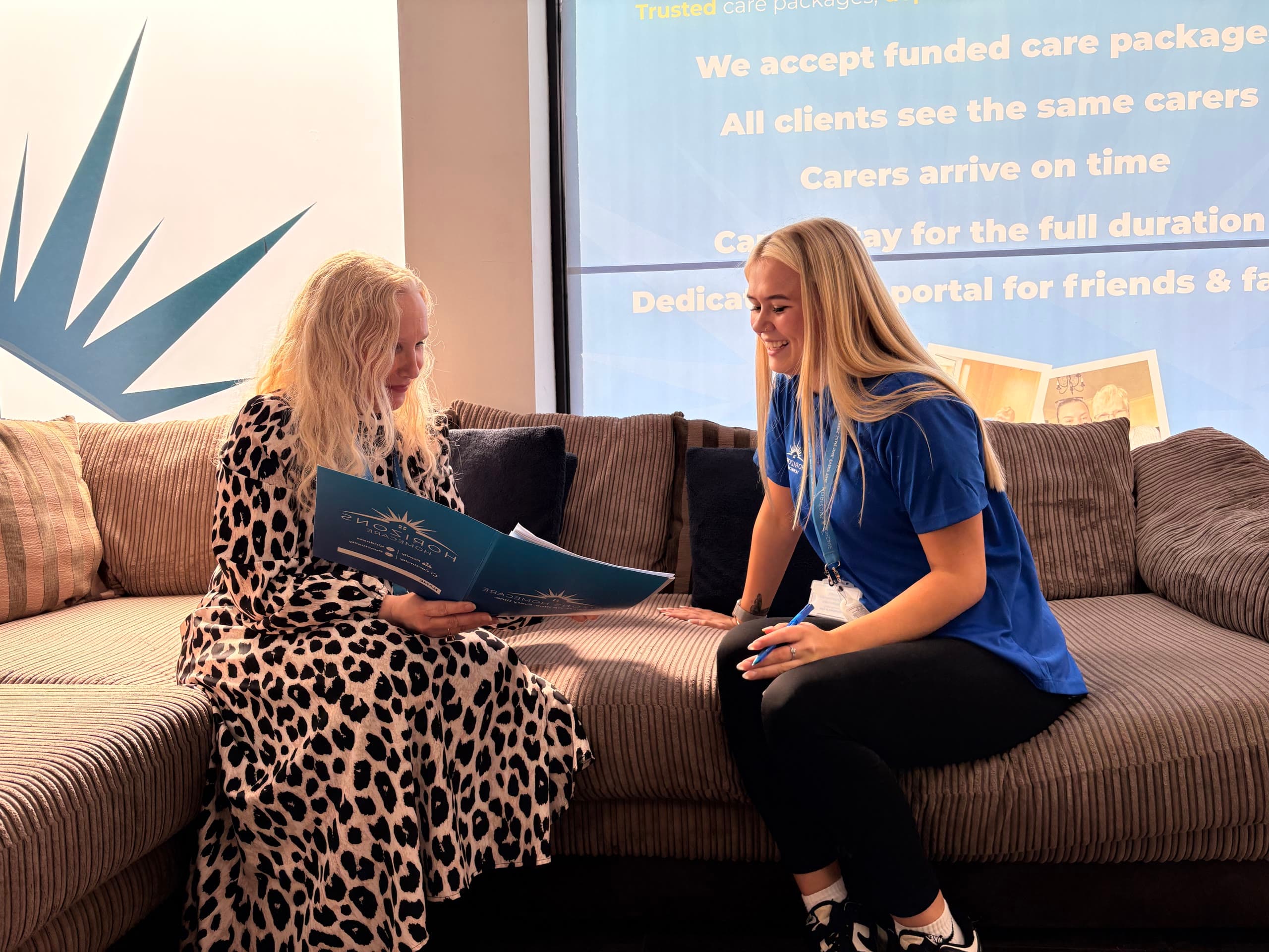 A Horizons Homecare team member smiling with a client as they look through a care folder together at our Lancaster branch